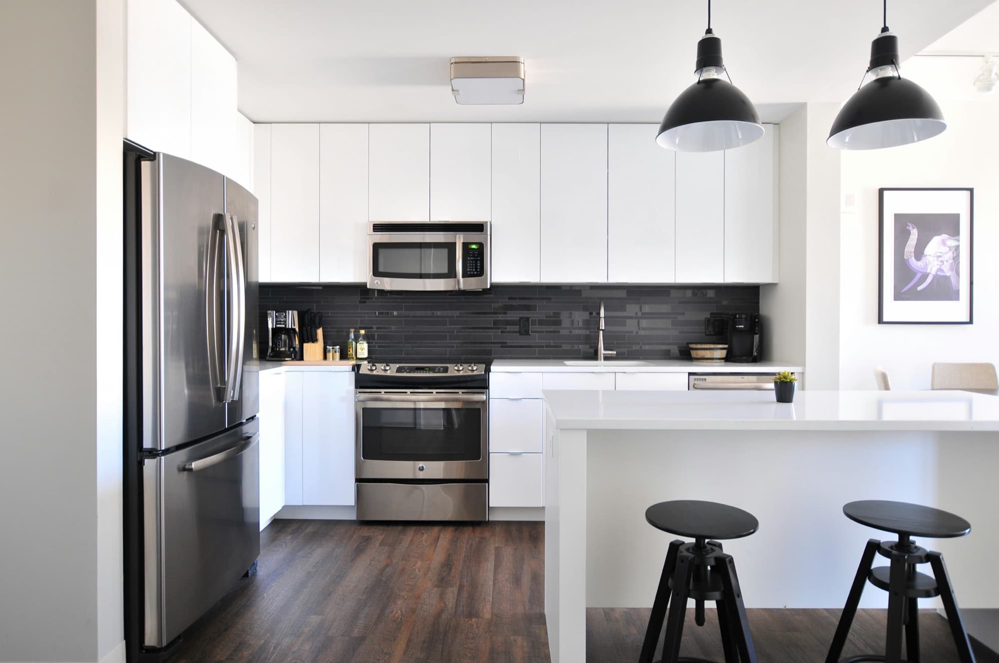 Modern white kitchen with stainless appliances and a spotless island